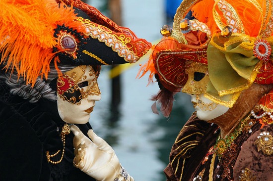 Two masked Venice carnival attendees admire each others' masks.