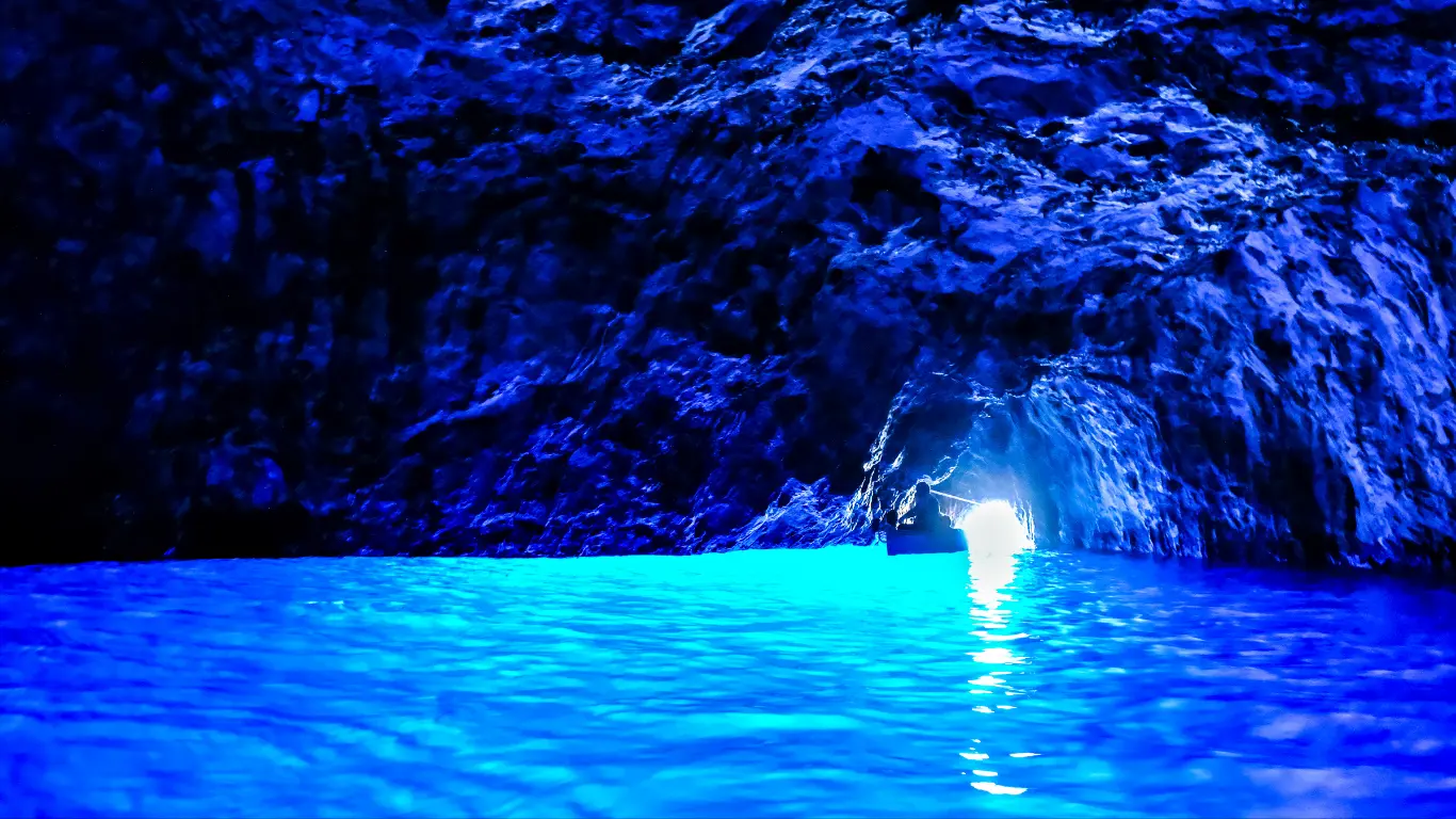 Boat entering the glowing Blue Grotto sea cave in Capri, Italy